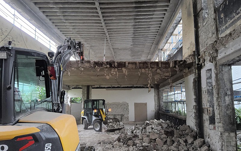 Abrissarbeiten in einer Industriehalle mit zwei Baggern und herabfallenden Betonteilen